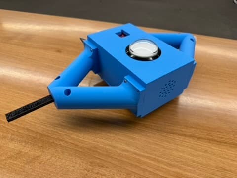Angled view of the blue DIY Bop It enclosure showing the arcade button, flexible arm, handles, and speaker ventilation