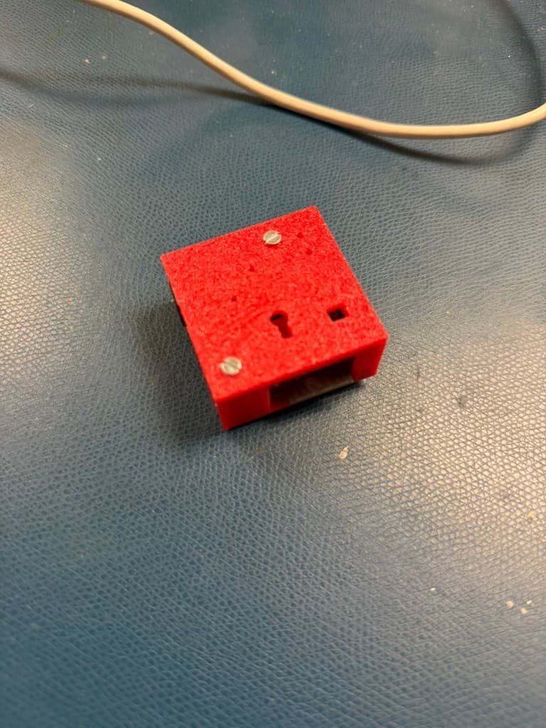 Rear view of the red embedded webcam enclosure showing its cable opening and mounting hardware
