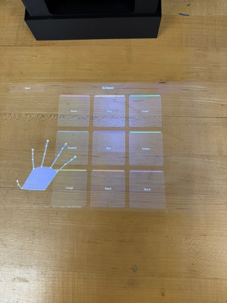 Close view of the projected DJ board with nine labeled sample pads and a hand-tracking graphic
